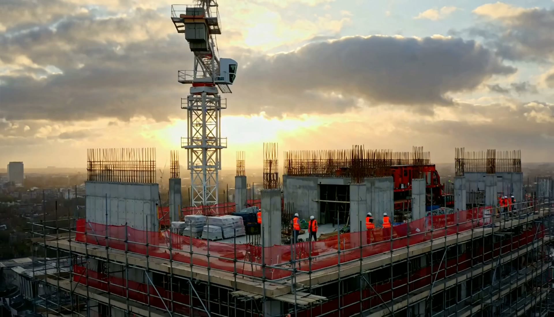 Large modern concrete and glass building under construction at dusk